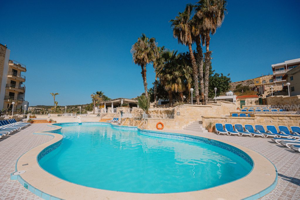 View of the pool with palm trees at Xemxija Bay Hotel in Malta